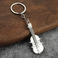 Portachiavi a forma di violino in argento lucido su sfondo in legno e grigio strutturato - Chitarra