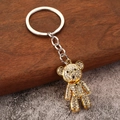 Portachiavi orso dorato di lusso con strass brillanti su sfondo industriale rustico - Oro