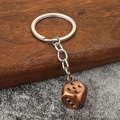Close-up of vintage bronze dice keychain with metallic finish on a textured background - Antique Red