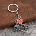 Détail du porte-clés I Love PAPA en métal émaillé sur un fond de texture contrastée - PAPA (I ❤️ PAPA)
