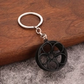 Detail of matte black car rim keychain with five-spoke design on a rustic wood background - Matte Black