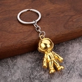 3D Goldener Astronaut Schlüsselanhänger mit Silberring auf Holz und Stein Hintergrund - Gold