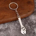 Miniature adjustable wrench keychain in polished silver metal on a rustic wood background - Adjustable Wrench