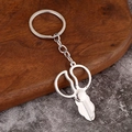 Polished silver metal scissors keychain with keyring on elegant wooden and stone background - Adjustable Scissors
