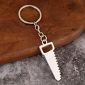 Detail of silver metal mini hand saw keychain pendant with realistic serrated edges - Saw