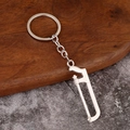 Detailed view of mini handsaw keychain tool with silver finish on rustic wood texture - Hacksaw
