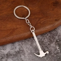 Polished silver metal keychain with miniature claw hammer tool on marble background - Hammer