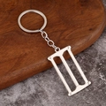 Detailed view of mini silver alloy hand saw keychain pendant on rustic wooden background - Woodworking Saw