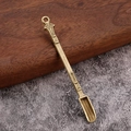 Détail macro d'une cuillère miniature en laiton vintage avec manche texturé et anneau supérieur - Bronze