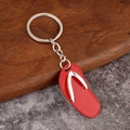 Creative red flip flop keychain with silver metal straps on a rustic wooden tray - Red
