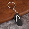 Detailed view of creative mini flip-flop keychain with polished metal strap and black base - Black