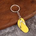 Creative yellow flip-flop keychain with silver metal ring and chain on a modern surface - Yellow