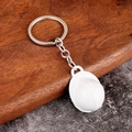Detailed view of a white mini safety helmet keychain resting on a wooden tray - White