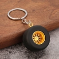 Close-up of a 3D car tire keychain with a gold wheel hub and realistic rubber textures - Gold
