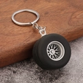 Detail view of mini car tire keychain with black rubber tread and silver metal wheel hub - Silver