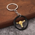 Macro detail of a 3-spoke racing steering wheel keychain in black and gold metal - Gold