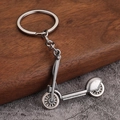 Close-up of vintage industrial style silver metal scooter keychain on a rustic wooden table - Antique Silver Skateboard