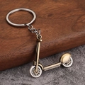 Detail of vintage bronze scooter keychain with retro metal texture on wooden surface - Antique Bronze Skateboard