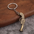 Vintage bronzen revolver sleutelhanger met antieke afwerking op hout en steen decor - Stijl A Revolver (Antiek Brons)