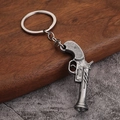 Detailopname van een vintage metalen pistool sleutelhanger op hout en stenen achtergrond - Stijl A Revolver (Antiek Tin)