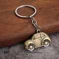 Nahaufnahme eines Vintage Käfer-Schlüsselanhängers aus Bronze auf einem Holztisch - Bronze