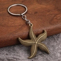 Vintage bronze starfish pendant keychain with metallic texture on rustic wooden background - Bronze