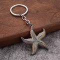 Macro detail of iridescent rainbow starfish keychain with textured finish on wood surface - Iridescent