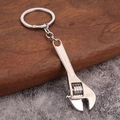 Miniature silver adjustable wrench keychain made of polished metal on wooden background - White K/Silver