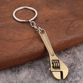 Detail of vintage bronze adjustable wrench keychain with industrial gear design on wood - Bronze