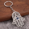 Nahaufnahme vom Hamsa-Hand-Schlüsselanhänger mit blauem Auge auf Holzgrund - Große Hamsa Hand (H-0301)