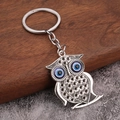 Detailaufnahme einer Eulen-Schlüsselanhänger mit blauen Evil Eye Perlen auf Holzdekor - Eule Stil 3 (H-0301)