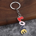 Colorful LOVE letter keychain with metal lobster clasp on a textured wooden background - Red