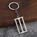 Macro view of realistic 3D mini hand saw keychain made of polished silver alloy - Woodworking Saw