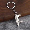Detailed macro view of a 3D silver metal power drill keychain on a textured background - Electric Drill