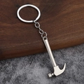 Close-up of claw hammer keychain made of matte silver alloy on a textured stone background - Hammer