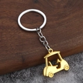 Detailed view of creative golden 3D golf cart keychain on stone and wood background - Gold