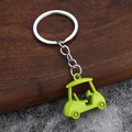 Dettaglio di un portachiavi a forma di golf cart verde in miniatura con anelli metallici su sfondo - Verde