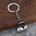 Macro detail of a 3D silver golf cart keychain with steering wheel on wooden background - Antique Pewter