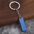 Kreativer blauer Mini-Roller Schlüsselanhänger mit silbernem Ring auf Holzoberfläche - Blau