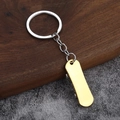 Detail shot of the golden metal miniature scooter keychain on a textured surface - Gold