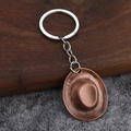 Vintage bronze western cowboy hat keychain made of zinc alloy on a rustic wood background - Antique Red