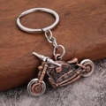 Porte-clés moto vintage en bronze avec roues mobiles sur un fond en bois rustique - Rouge Antique