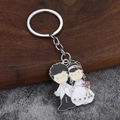 Vue détaillée du porte-clés émaillé mariés de dessin animé sur fond bois de noyer et pierre - Couple en Costume de Mariage Style Mixte (011)