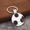 Close-up of a metal football keychain with classic patterns and bottle opener feature - Black Soccer