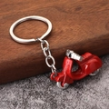 Detail of red alloy motor scooter keychain with silver handlebars on rustic background - Red