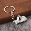 Macro shot of white alloy Vespa-style scooter keychain with silver ring on wooden base - White