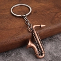 Détail d'un porte-clés saxophone en bronze vintage sur une surface en bois et tapis - Style B (Saxophone) - Rouge Antique