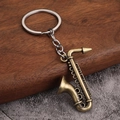 Detalle de un llavero de saxofón de bronce vintage sobre una superficie de madera - Estilo B (Saxofón) - Bronce Antiguo