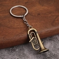 Llavero de trompeta de bronce vintage sobre un fondo de madera rústica con textura - Estilo A (Tuba/Bombardino) - Bronce Antiguo