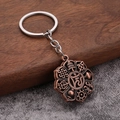 Detailed close-up of antique bronze Buddhist Om pendant on a polished metal keychain - Antique Red